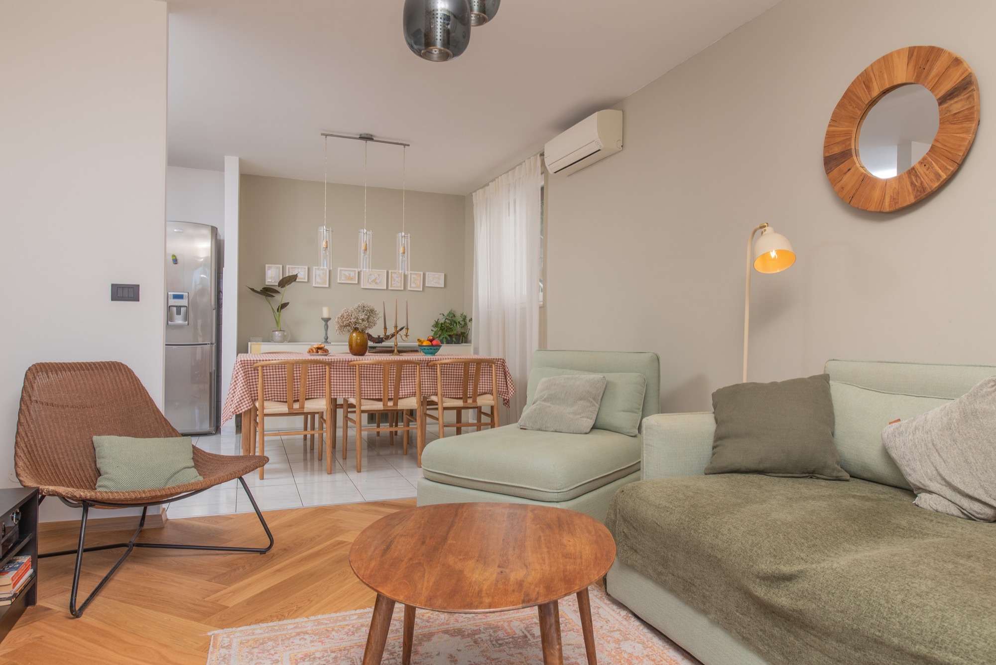 Open-plan living and dining area with sage sofa and checkered table