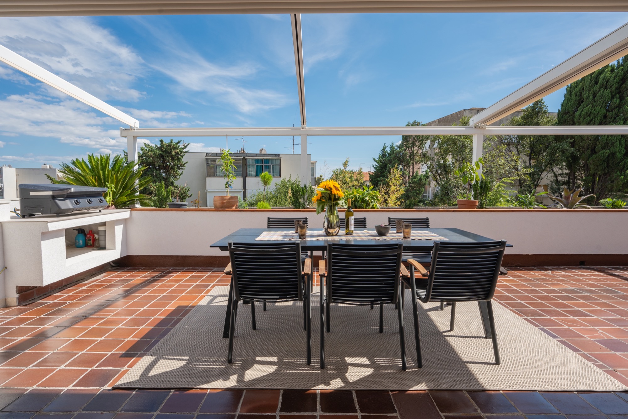 Sunny terrace dining table with sunflowers and a built-in outdoor grill