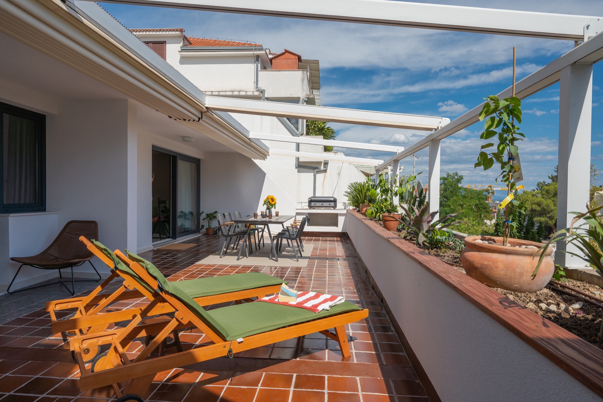 Wooden sun loungers on the terrace overlooking trees and the sea